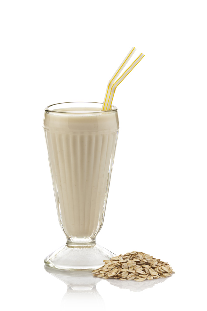 picture of a milkshake made from oats with two yellow straws against a white background