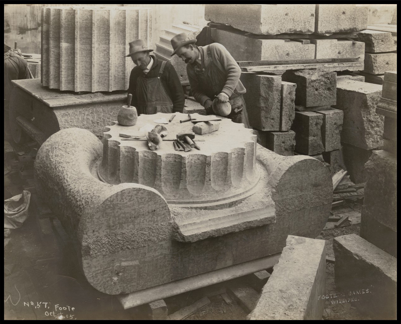 Photo of two men working on the top of a giant exterior column.