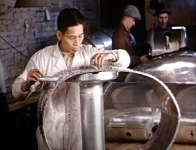 men in a factory work on large, round metallic objects