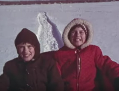 two grinning children are sledding
