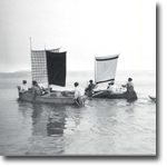 photo of men in boats using point blankets for sails