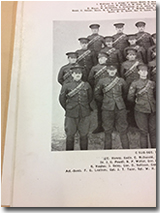 photo of a page in the Second Contingent, Military District No. 10 1915 booklet, with a group of men standing in uniform, with their names indicated below the photo. Frank Leathers is the second man in the front row.