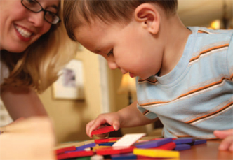 boy playing with toys with a woman smiling at him