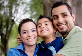 two adults and a child hugging and smiling at the camera