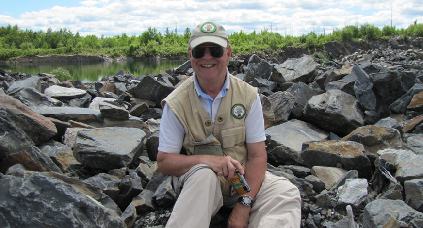 A ROCK STAR: Sitting on a pre-Cambrian phyllite outcrop, Jim Bamburak is nearing the end of his career and is encouraging budding geologists.