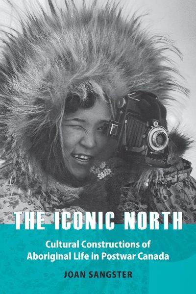 Book cover for the Iconic North showing an Inuk person taking a photograph with a film camera. The hood of their parka is up and they squint looking though the lens. 