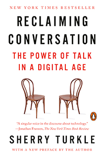 Book cover for Reclaiming Conversation: The Power of Talk in a Digital Age. The design features two wooden chairs facing each other on a white background.