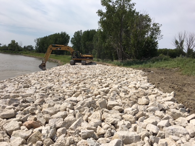 excavator reinforcing shore with rocks