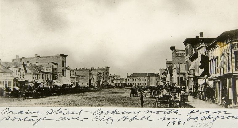 Vue de la rue Main, vers le nord,  partir de lavenue Portage; on y voit une large chausse boueuse et des trottoirs de bois.