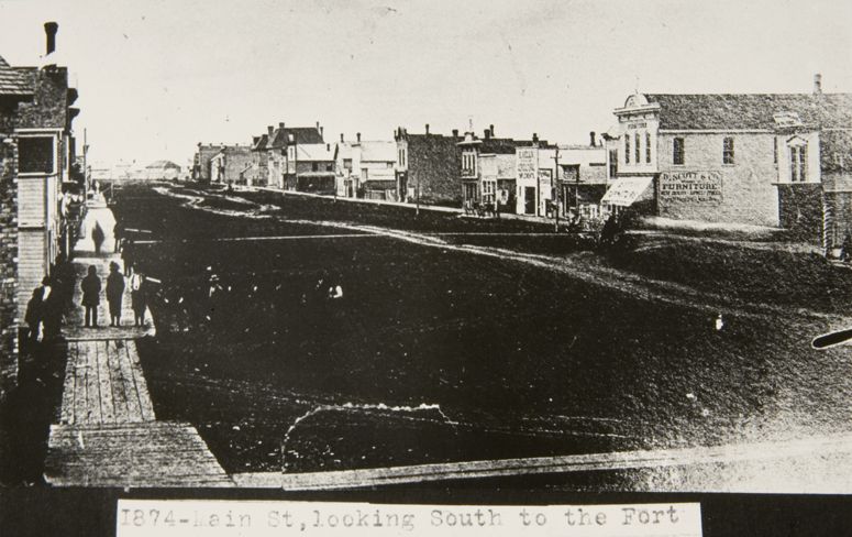 Vue de la rue Main, vers le sud, a partir de lavenue Graham; on y voit une large chausse boueuse et des trottoirs de bois.